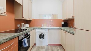 Une cuisine compacte équipée d’un lave-linge, d’une machine à café et d’un four à micro-ondes.