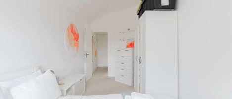 A hotel room with a bed, a desk, a wardrobe, and a storage unit.