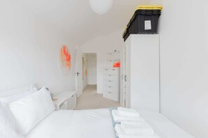 Una habitación de hotel con cama, escritorio, armario y espacio de almacenamiento.