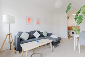Ein modernes Wohnzimmer mit einem grauen Sofa, einem Holztisch und einer Stehlampe.