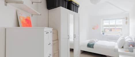 A bedroom with a bed, a wardrobe, a desk, a window, and storage boxes on the wall.