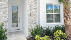 A modern house with a stone facade, a white door, and a window with blinds. - Modern 3Bd Screened Pool at Serenity Resort 17322 (Clermont)