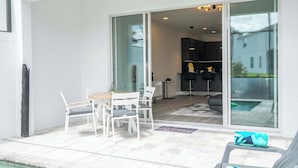 A modern outdoor patio with a dining set, a pool, and a view of the backyard. - Modern 3Bd Screened Pool at Serenity Resort 17322 (Clermont)