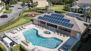 A residential building with a swimming pool, solar panels, and a fenced patio area. - Modern 3Bd Screened Pool at Serenity Resort 17322 (Clermont)