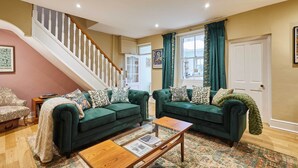 A living room with two green sofas, a wooden coffee table, and a staircase. - Host Stay Sonsy Cottage (Alnwick)
