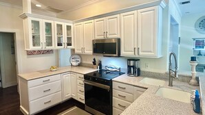 Une cuisine moderne avec des meubles blancs, une cuisinière en acier inoxydable et un four à micro-ondes encastré.