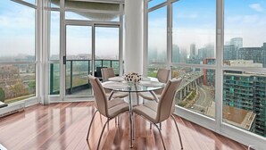 A modern dining area with a glass table and chairs, large windows offering city views, and a white pillar. - Atlantis at Waterpark City Condos in DT (Toronto)