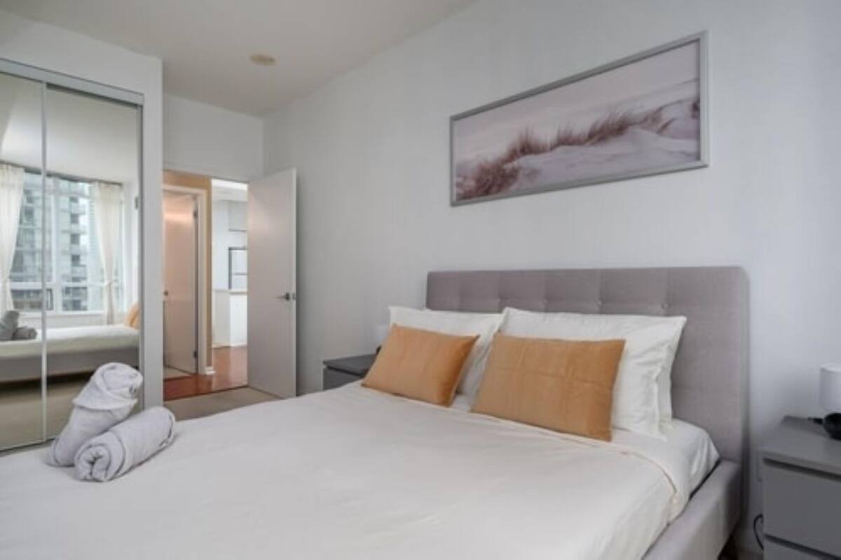 A hotel room with a bed, a nightstand, a wall-mounted picture, and a sliding glass door leading to a balcony.