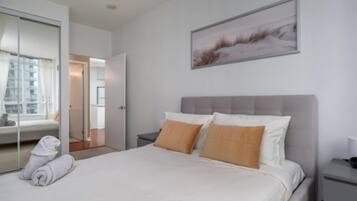 A hotel room with a bed, a nightstand, a wall-mounted picture, and a sliding glass door leading to a balcony.