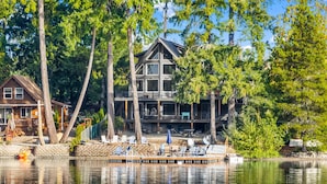 Eine Blockhütte am See mit einem Steg, umgeben von Bäumen.