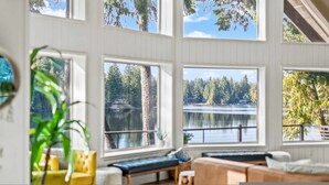 Ein geräumiges Zimmer mit großen Fenstern und Blick auf See und Wald.
