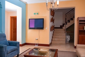 A hotel lobby with a flat-screen TV, a blue sofa, a coffee table with a bowl, and a staircase. - Mar... Guesthouse (Lobito)