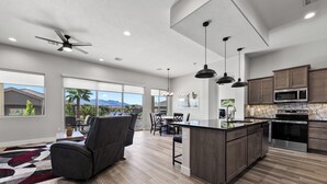 Une cuisine moderne dotée d’un îlot central, de meubles en bois foncé, d’appareils électroménagers en acier inoxydable et d’une grande fenêtre donnant sur un paysage magnifique.