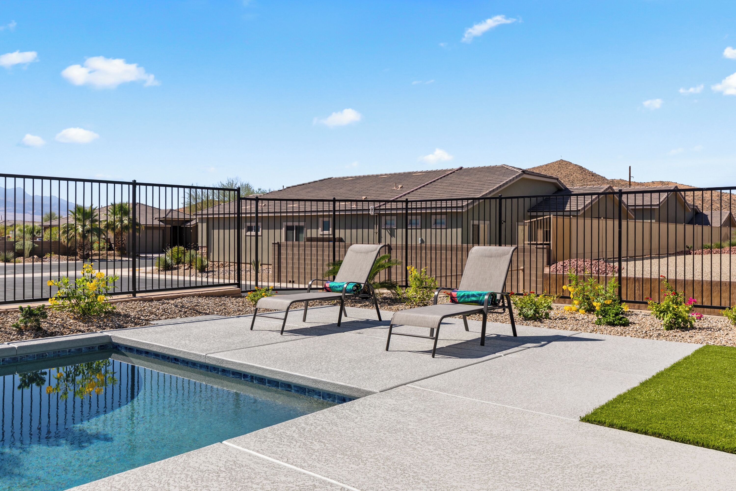 A swimming pool with lounge chairs and a fence.