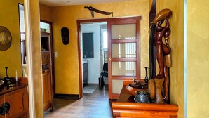 A hallway with a wooden door leading to a bathroom, a small table with a bowl and a vase, and a wall-mounted sculpture. - CHAMBRE VIVIANE in the Mélusine house near the Brocéliande forest (Néant-sur-Yvel)
