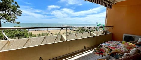 A balcony with a view of the beach and ocean.