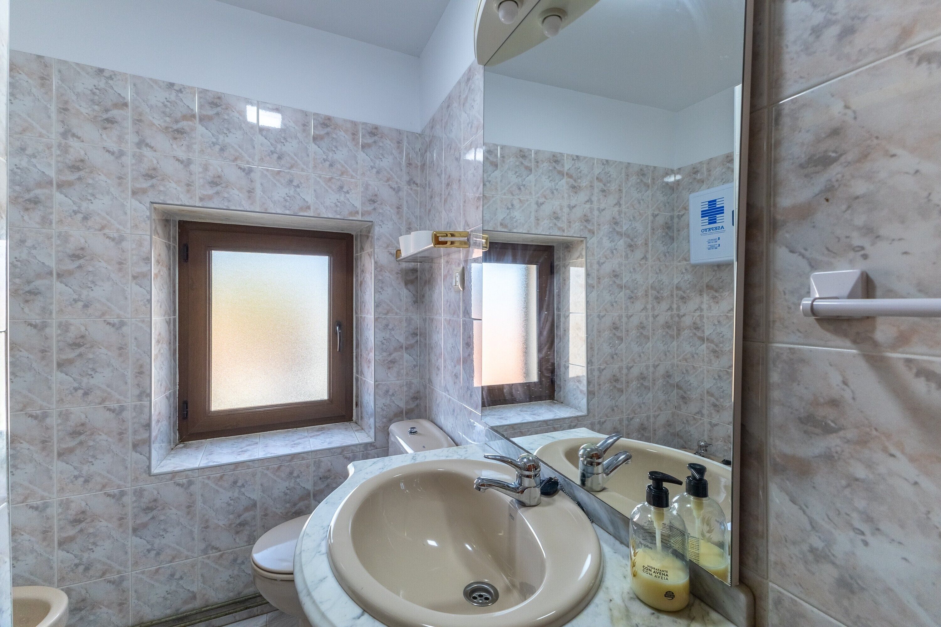 Un baño con un lavamanos grande, un inodoro y una ventana.