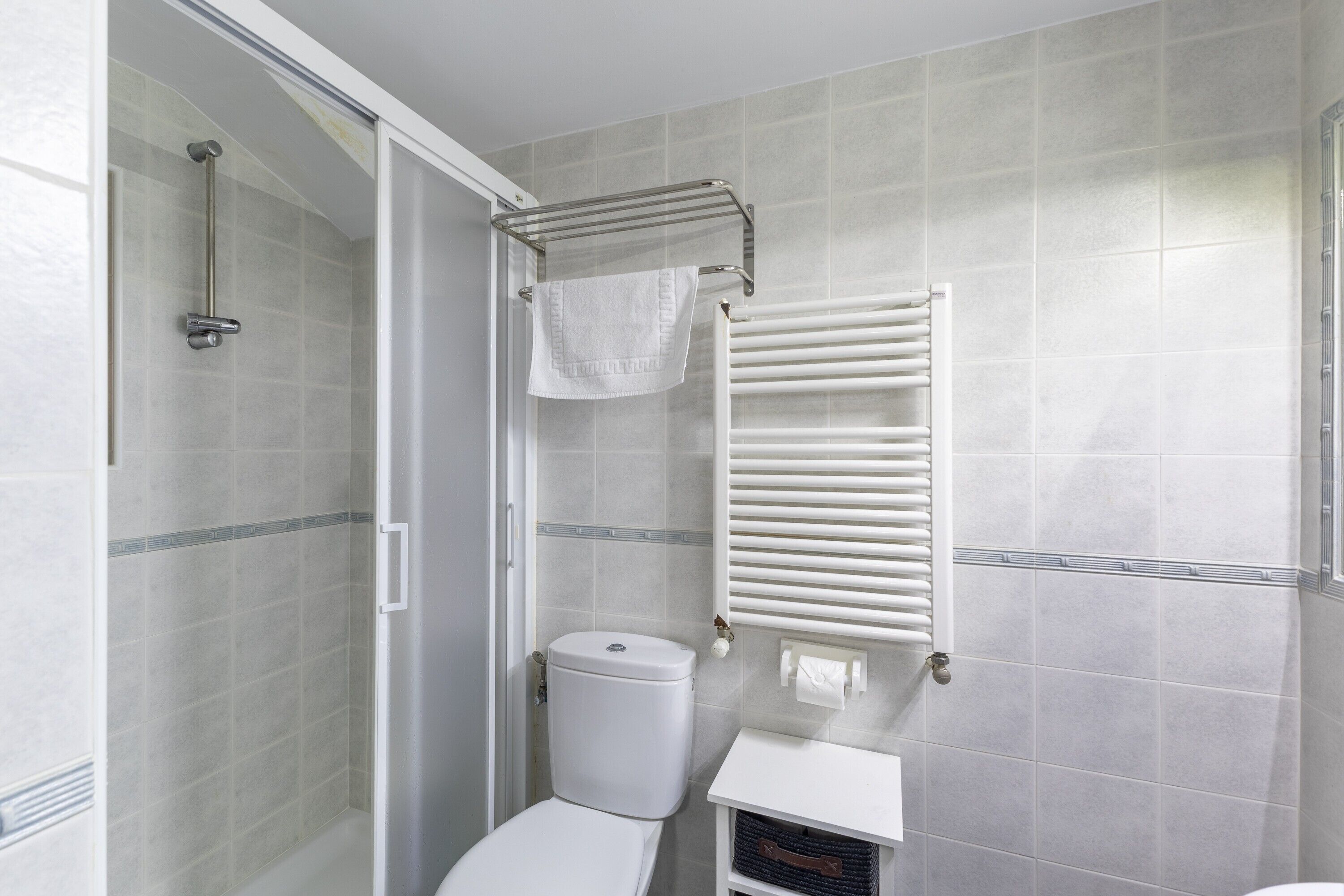 Een badkamer met een douche, toilet en handdoekrek.