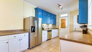 A modern kitchen with stainless steel appliances, white cabinetry, and a blue accent wall.