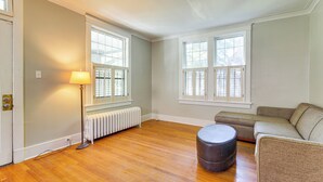 Ein Zimmer mit Holzböden, einem Heizkörper, einer Lampe und einem Ecksofa.