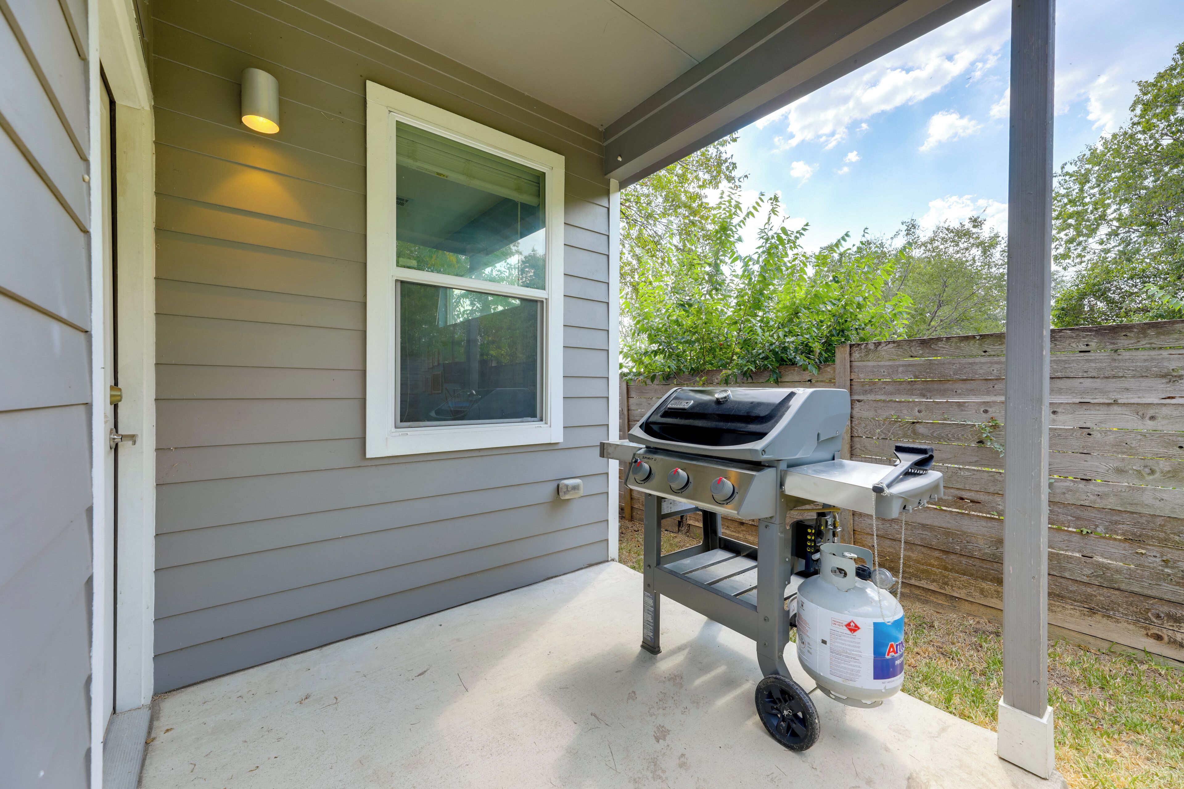 Un patio couvert équipé d’un barbecue intégré et d’une bouteille de propane.