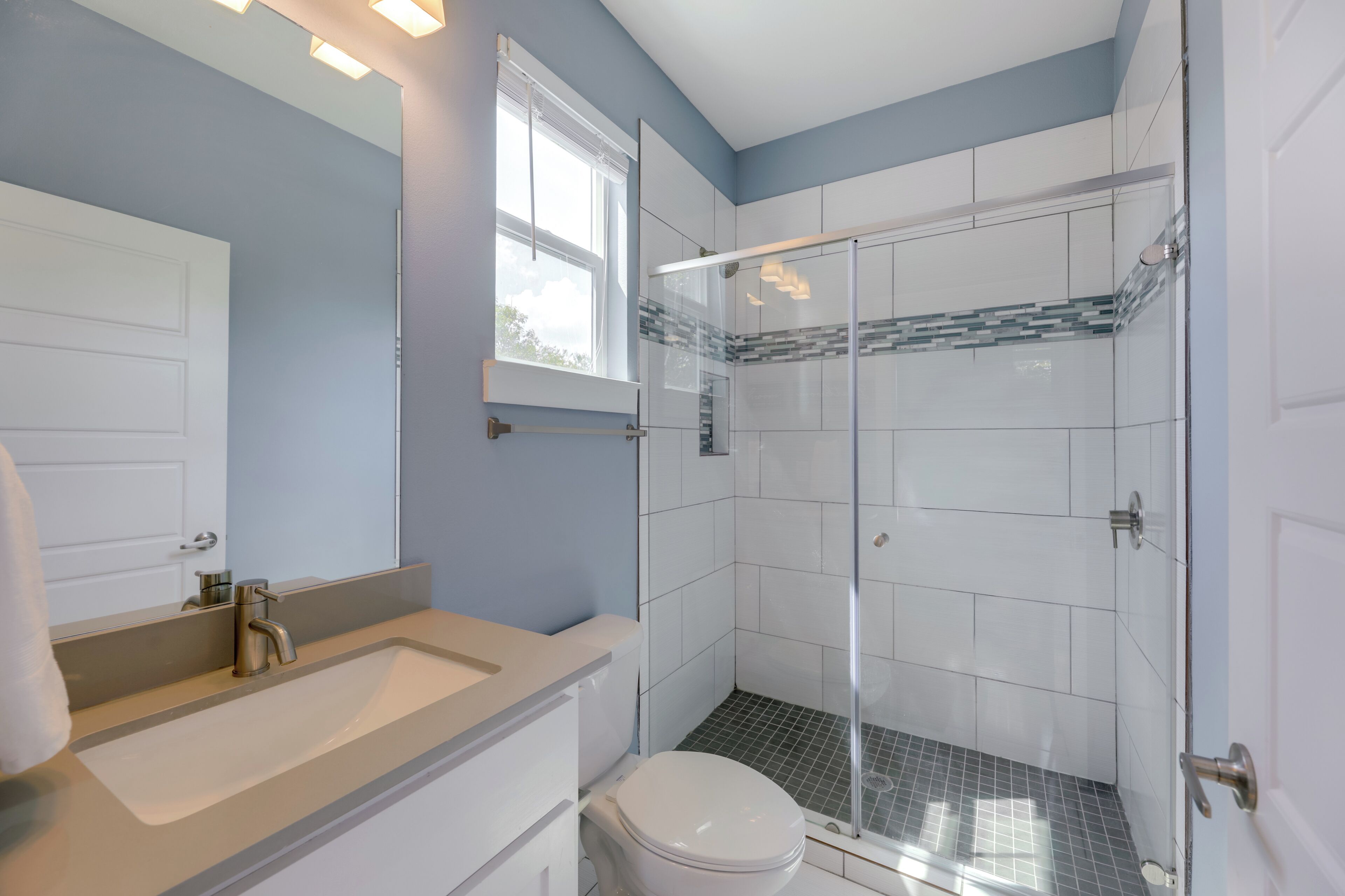 A bathroom with a sink, toilet, and glass shower enclosure.