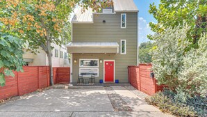 A two-story building with a red door, a covered entryway, and a small patio area with chairs. - Cowboy Pool & Balcony: Home 1 Mi to Dtwn Austin! (Austin)