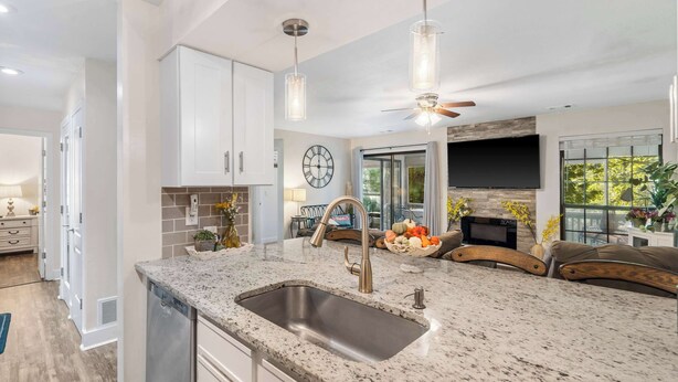 A kitchen with a granite countertop, stainless steel sink, and a ceiling fan. - Cute, Comfy & Cozy - For 6 (Branson)