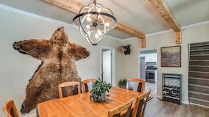 Un coin repas agrémenté d’un grand tapis en fourrure, de chaises en bois, d’un lustre et d’une table à manger.