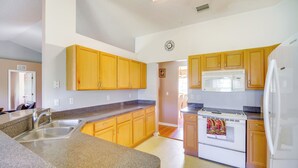 A kitchen with granite countertops, wooden cabinets, a stainless steel sink, a white refrigerator, and a white stove. - Spacious Palm Bay Stay! Family Home Near Beaches (Palm Bay)