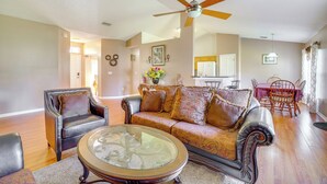A living room with a ceiling fan, a sofa, a coffee table, and a dining area with chairs and a table. - Spacious Palm Bay Stay! Family Home Near Beaches (Palm Bay)