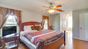 A bedroom with a wooden bed, a ceiling fan, and a television on a wooden stand. - Spacious Palm Bay Stay! Family Home Near Beaches (Palm Bay)