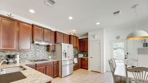 A modern kitchen with wooden cabinets, stainless steel appliances, and a tiled floor. - 5 Mi to Lake Travis: Pet-friendly Home w/ Yard! (Lakeway)