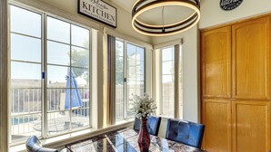 A dining area with a marble table, blue chairs, and a vase of flowers. - Pool, Games & Patio Bar! Epic Bullhead City Oasis (Bullhead City)