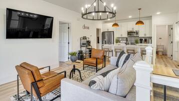 A modern living room with a sofa, chairs, a coffee table, and a TV mounted on the wall.