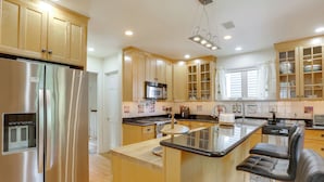 A modern kitchen with wooden cabinets, stainless steel appliances, and a central island with seating. - Walk to Hudson River Waterfront: Newburgh Home (Newburgh)