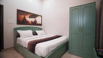 Une chambre à coucher avec un lit, une armoire verte et un tableau accroché au mur.