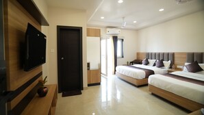 A modern hotel room with two beds, a flat-screen TV, a ceiling fan, and a large window. - Pearl of Varanasi (Varanasi)