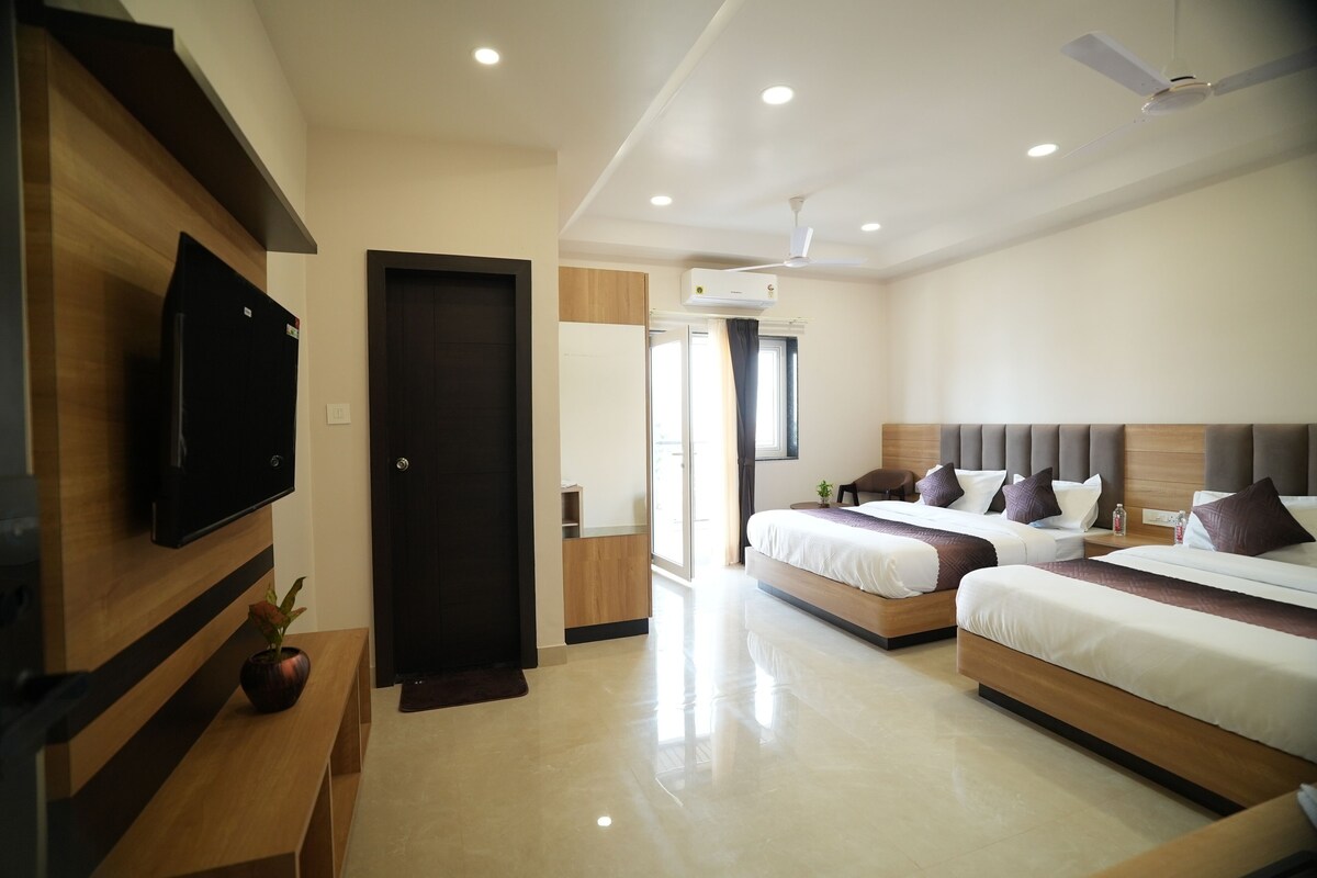 A modern hotel room with two beds, a flat-screen TV, a ceiling fan, and a large window.