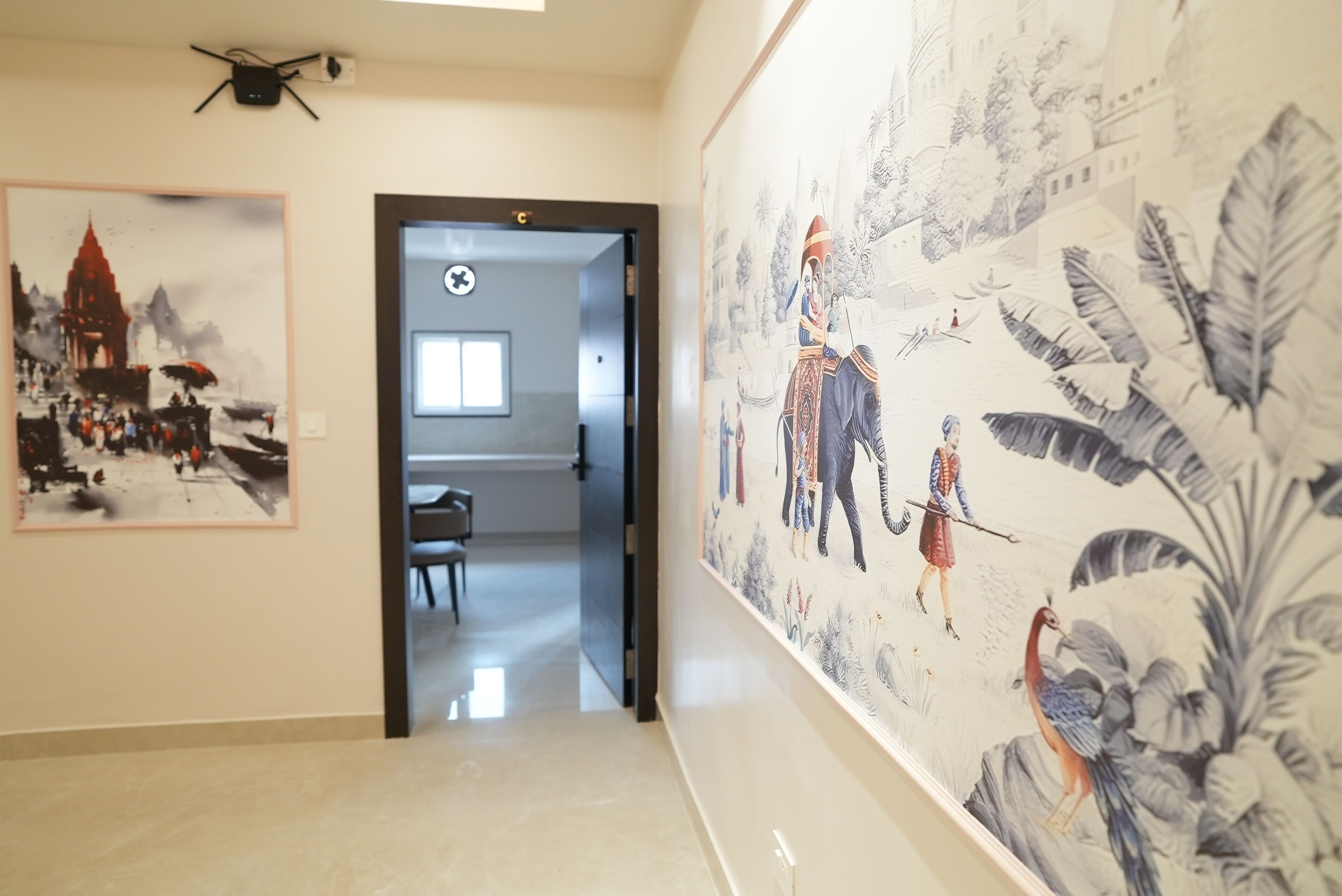 A hallway with a mural of a traditional scene, a door leading to a room, and a ceiling-mounted device.