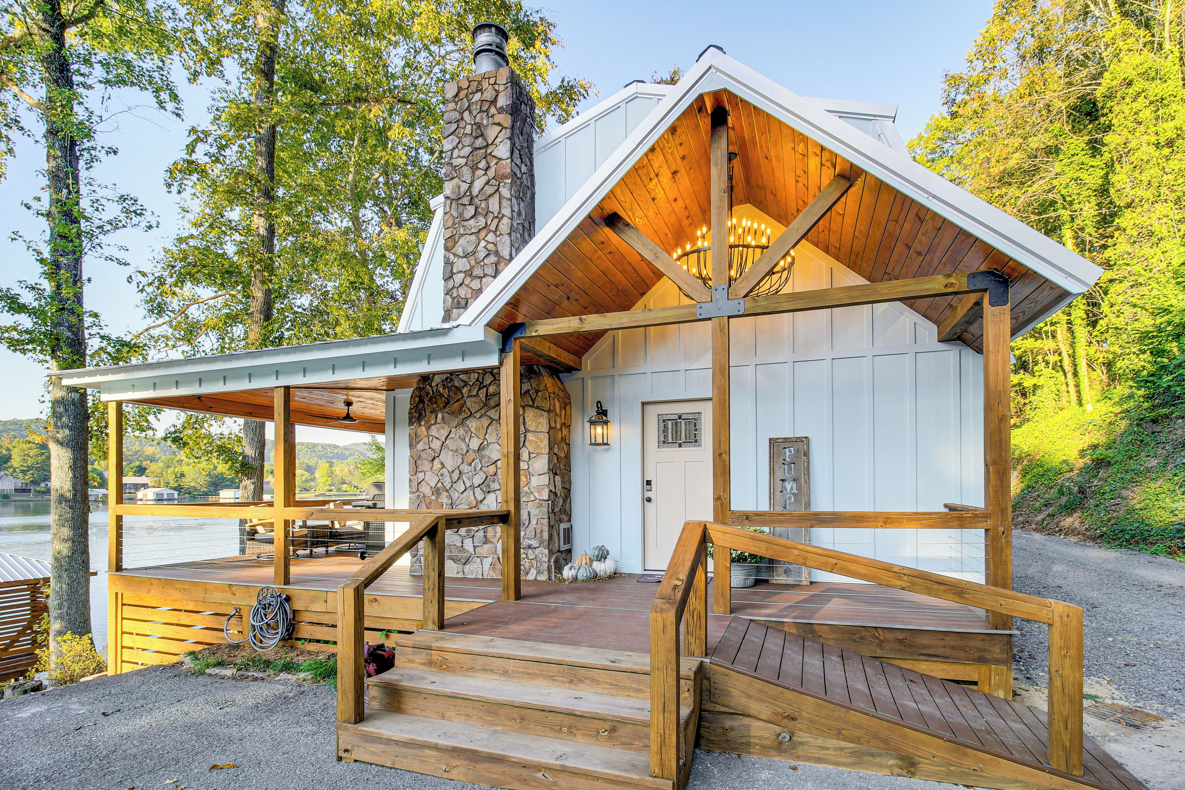 Une cabane avec une cheminée en pierre, une terrasse en bois et un porche couvert.