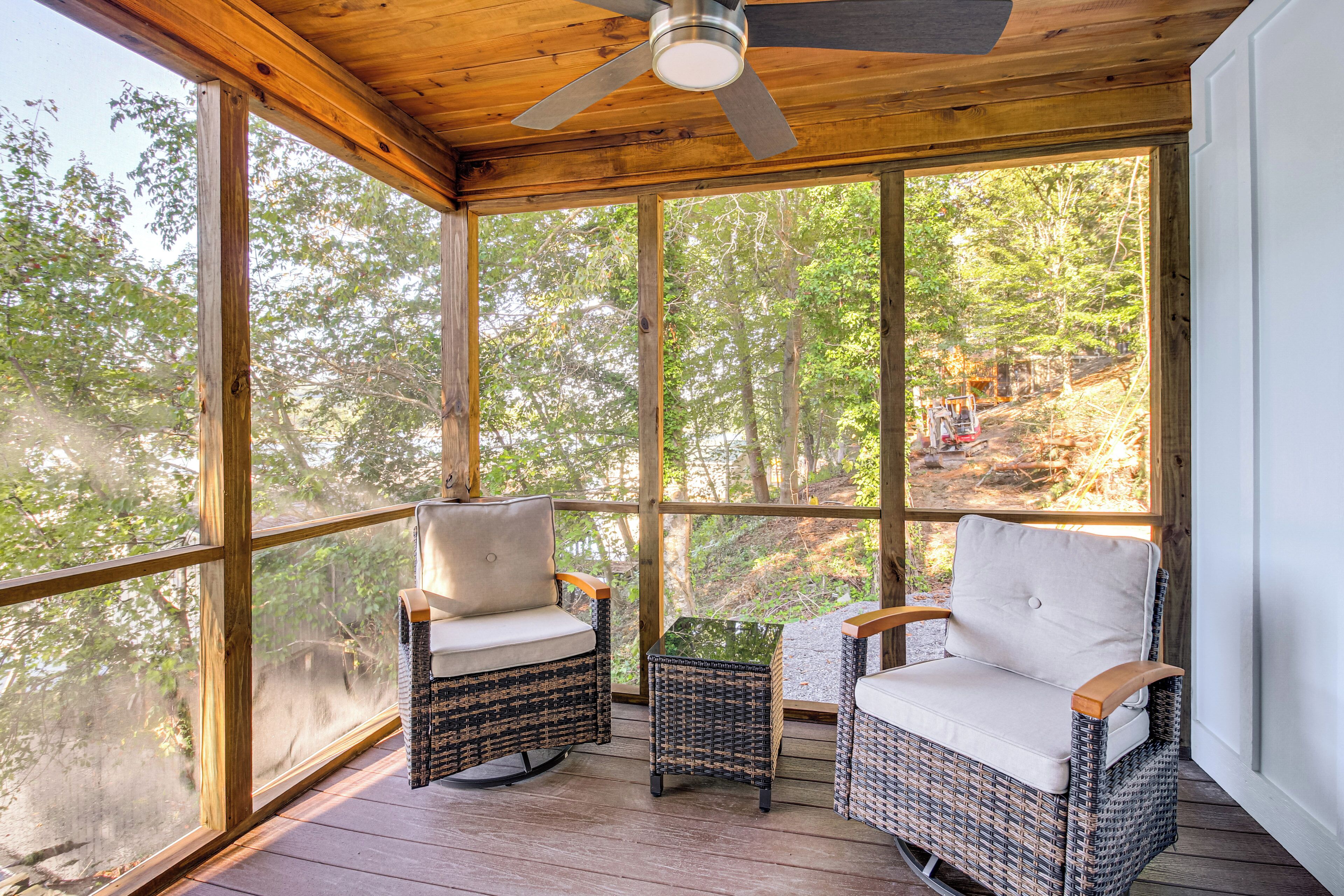 Une terrasse en bois, dotée de chaises et d’une table en osier, qui offre une vue sur une zone boisée.