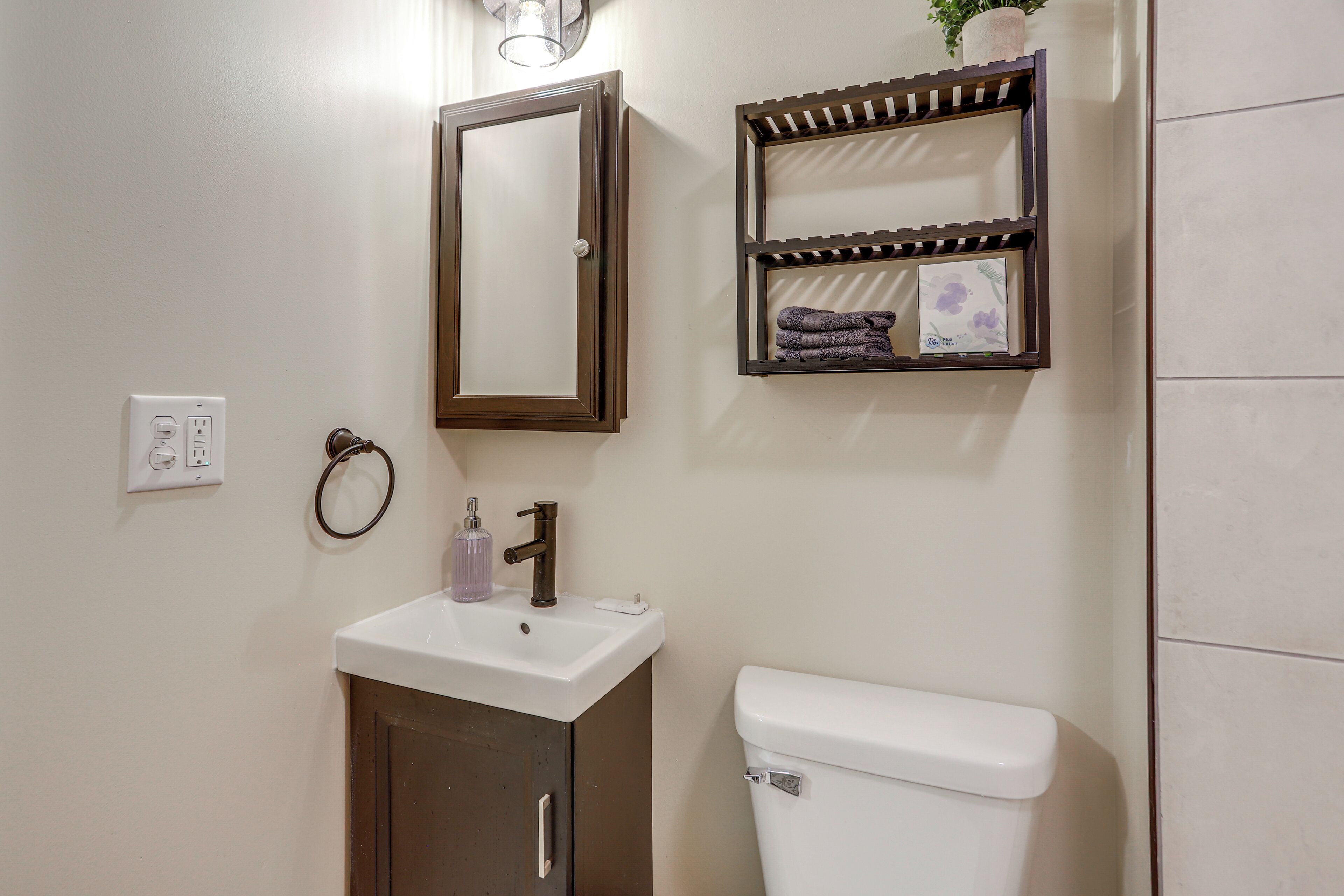 A bathroom with a white sink, a mirror, a toilet, and a towel rack.