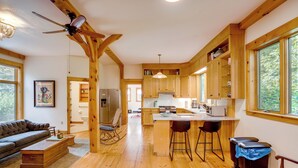 A spacious kitchen with wooden cabinets, a central island, and bar stools. - Secluded Family Getaway w/ On-site Creek in Hawley (Charlemont)