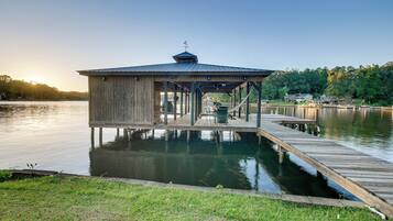 A wooden dock extending into a calm lake, with a covered pavilion at the end.