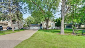 A residential driveway with a well-maintained lawn, a garage, and a house with a blue door. - 1 Mi to White Bear Lake & Dtwn: Twin Cities Escape (White Bear Lake)