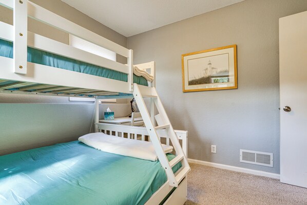 A bunk bed with a green mattress and white bedding, a framed picture on the wall, and a door with a white frame. - 1 Mi to White Bear Lake & Dtwn: Twin Cities Escape (White Bear Lake)
