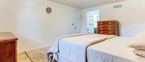 A bedroom with a bed, a wooden dresser, and a carpeted floor.