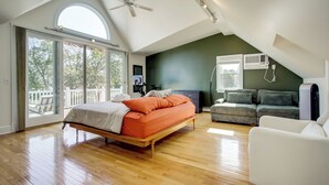 A spacious bedroom with a large bed, a ceiling fan, and a view through the sliding glass door. - Marinafront Cottage Sunrise, Fire Pit, Fireworks (Cambridge)