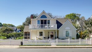 A two-story house with a balcony, a picket fence, and a front porch. - Marinafront Cottage Sunrise, Fire Pit, Fireworks (Cambridge)